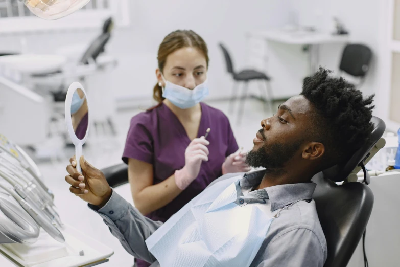 a dental worker checks the teeth of a woman in an examination room