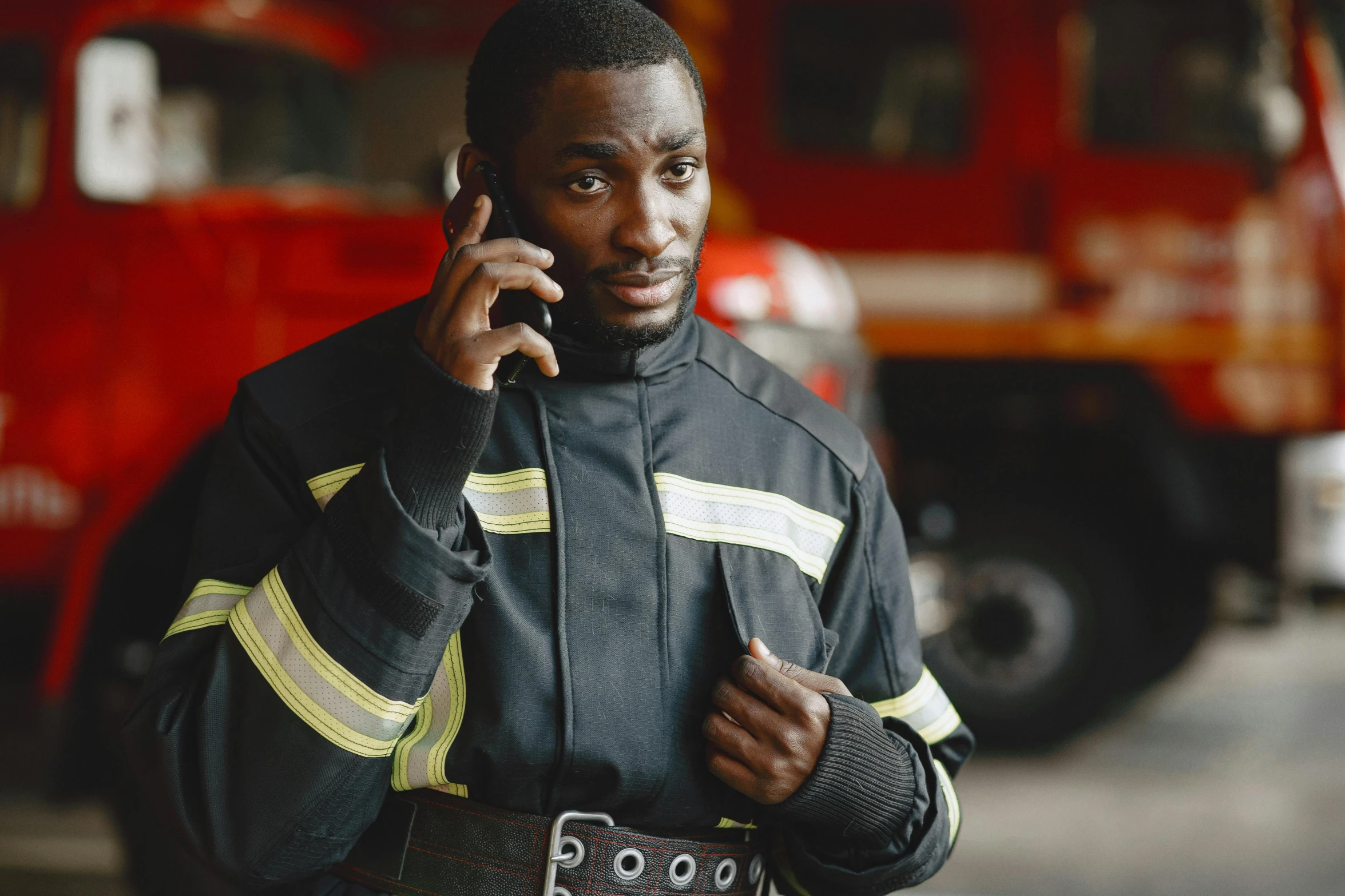 a firefighter standing in front of a truck talking on a cell phone