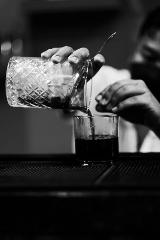 the bartender pours a drink from a glass into a glass