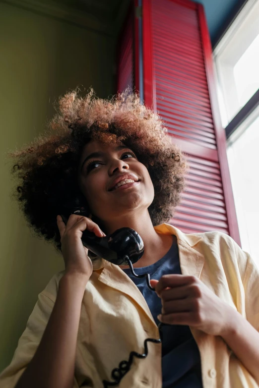 a lady sitting near a window talking on a cell phone