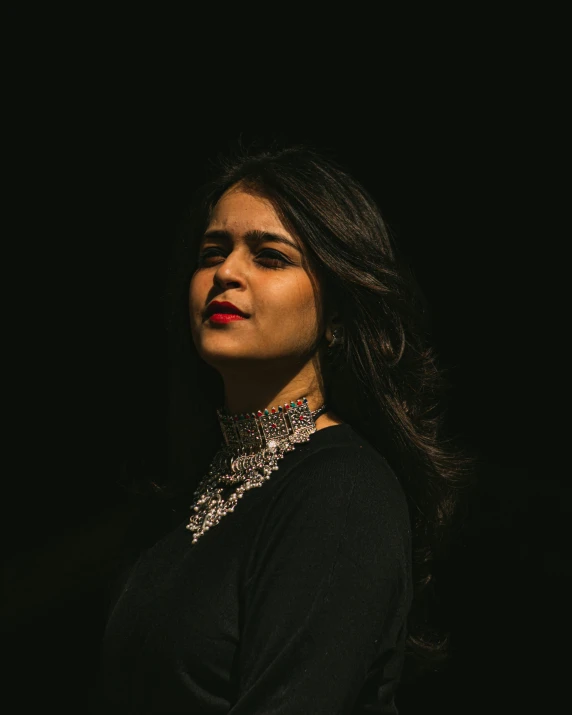 woman wearing a necklace against a dark background