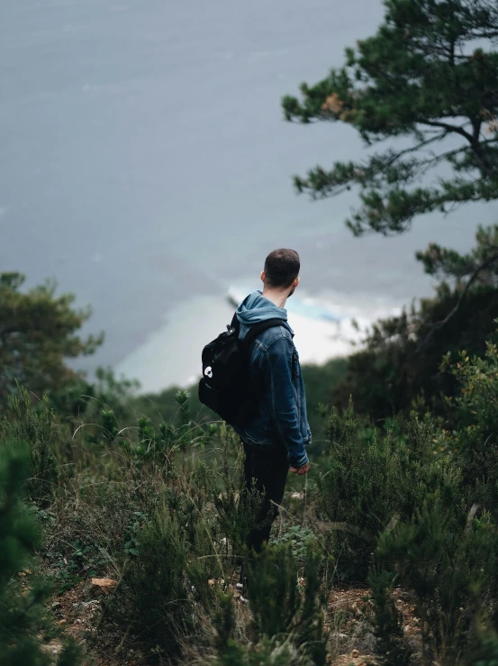 a man with backpack looking out over the wilderness from a cliff
