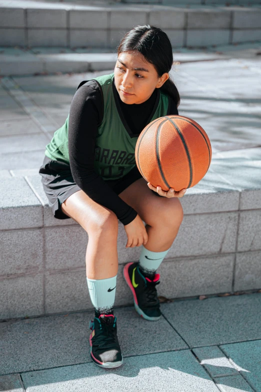 a girl squatting on steps holding a basketball