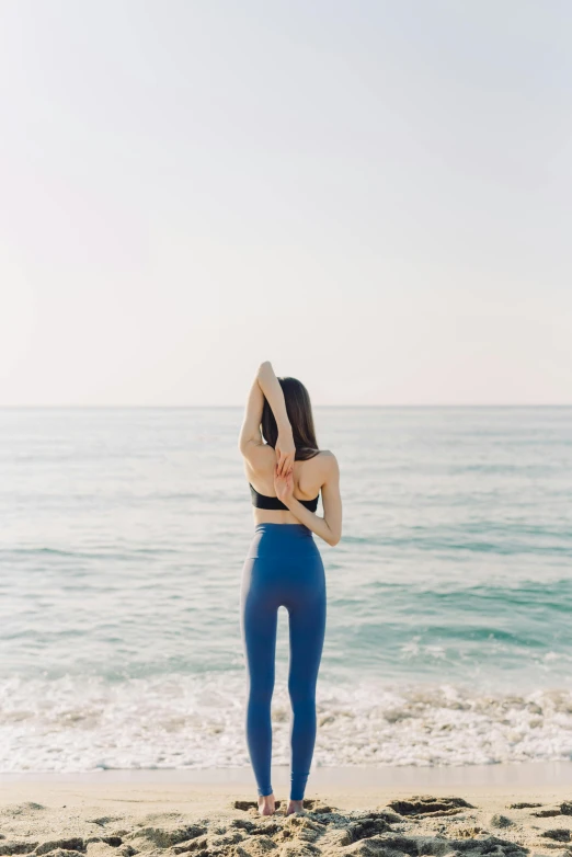 woman wearing blue leggings at the ocean on the beach