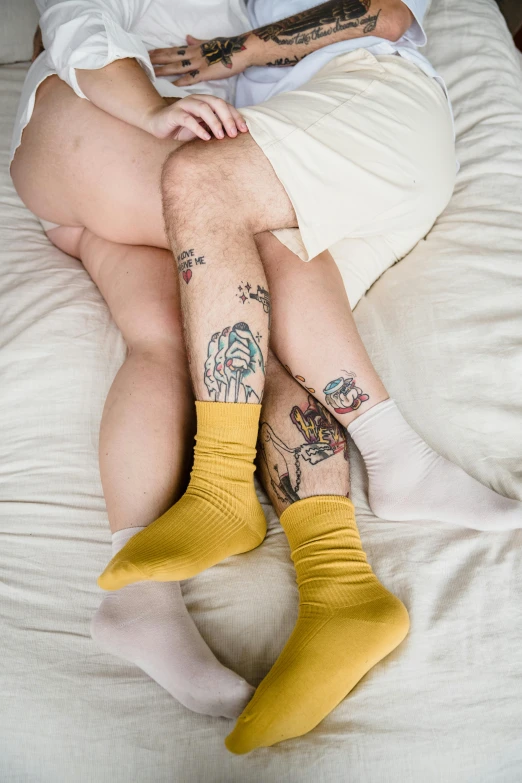 a person with tattoos sitting on top of a bed