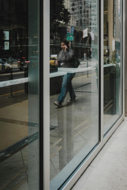 two people are walking by glass in the city