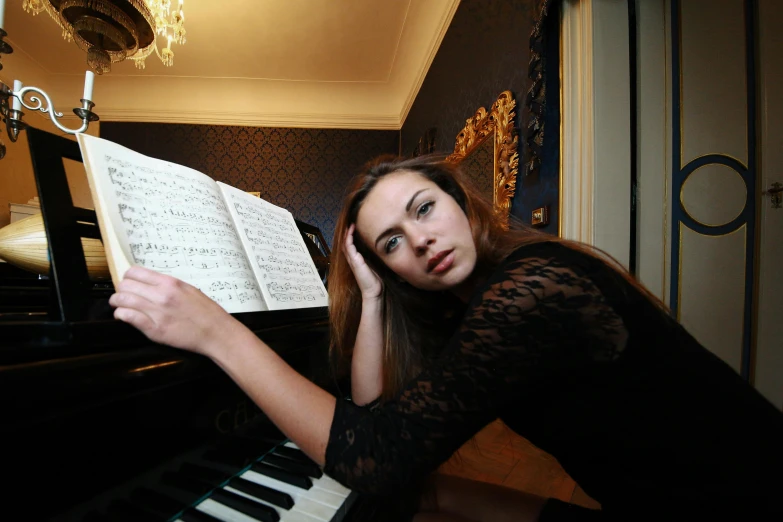 a woman in a black dress sitting at a piano