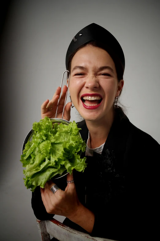 a woman smiles as she is holding a knife and lettuce