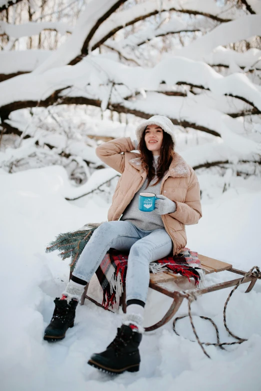 a girl is sitting in the snow with her hat on