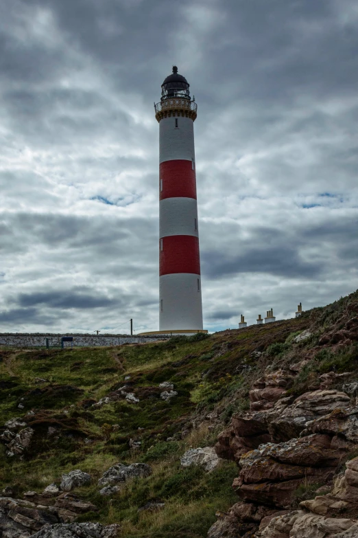 a large light house near some cliffs and green grass