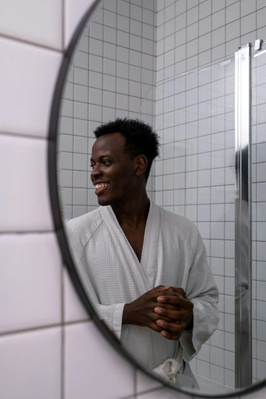 a man in a white robe is reflected in a bathroom mirror