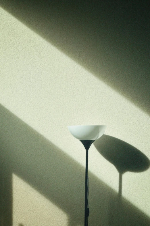 a lamp and two tables casting shadows on the wall