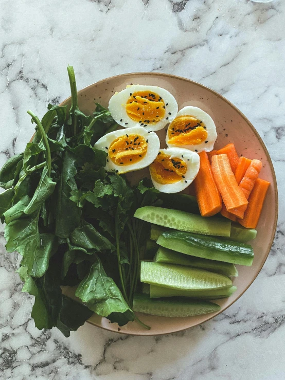 an assortment of veggies on a plate, including carrots, egg halves, and other fresh vegetables