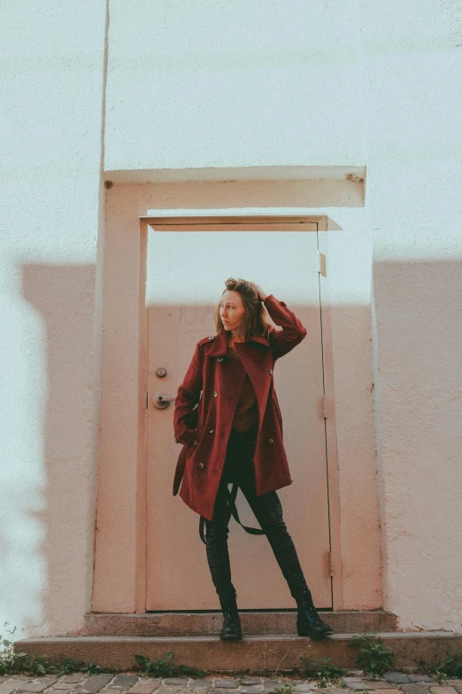 a woman in red coat posing on steps near doorway