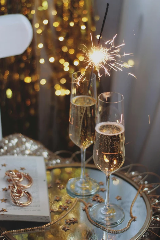 two glasses of champagne are on a tray with a gift