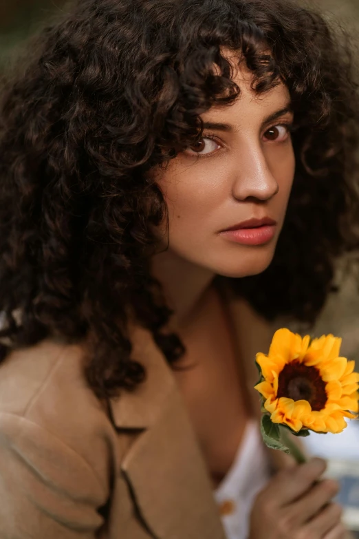 a woman is holding a sunflower in her hand