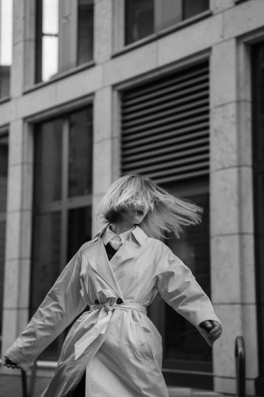 a woman in a trench coat, with her hair falling