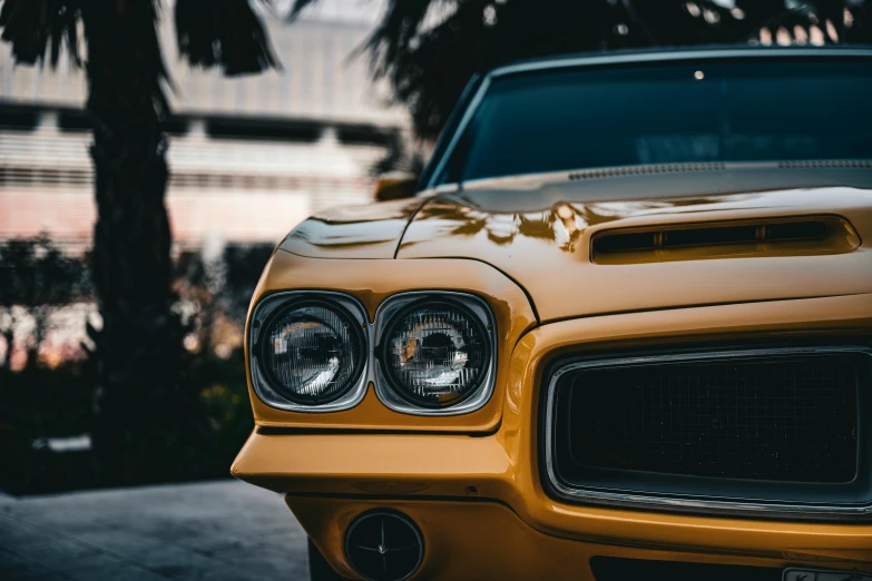 the headlight and lights of an older yellow car