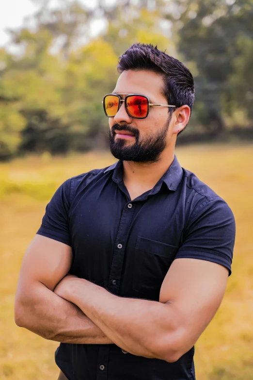 a man wearing sunglasses posing in front of a field
