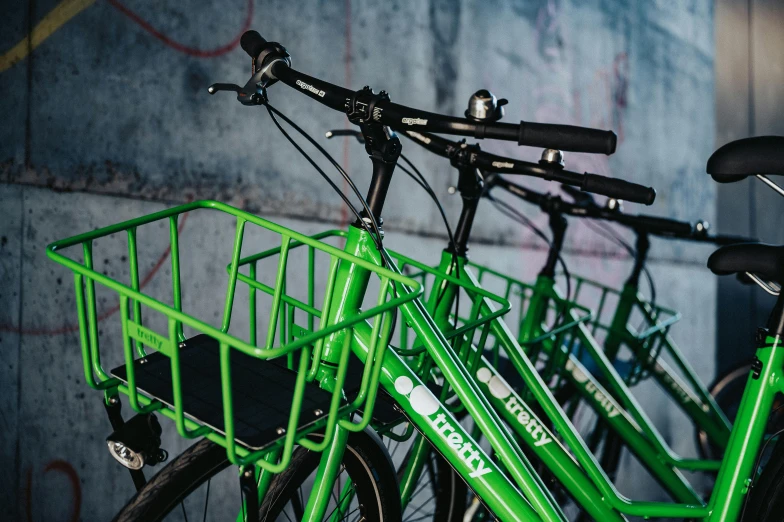 two green bicycles leaning on each other against a wall