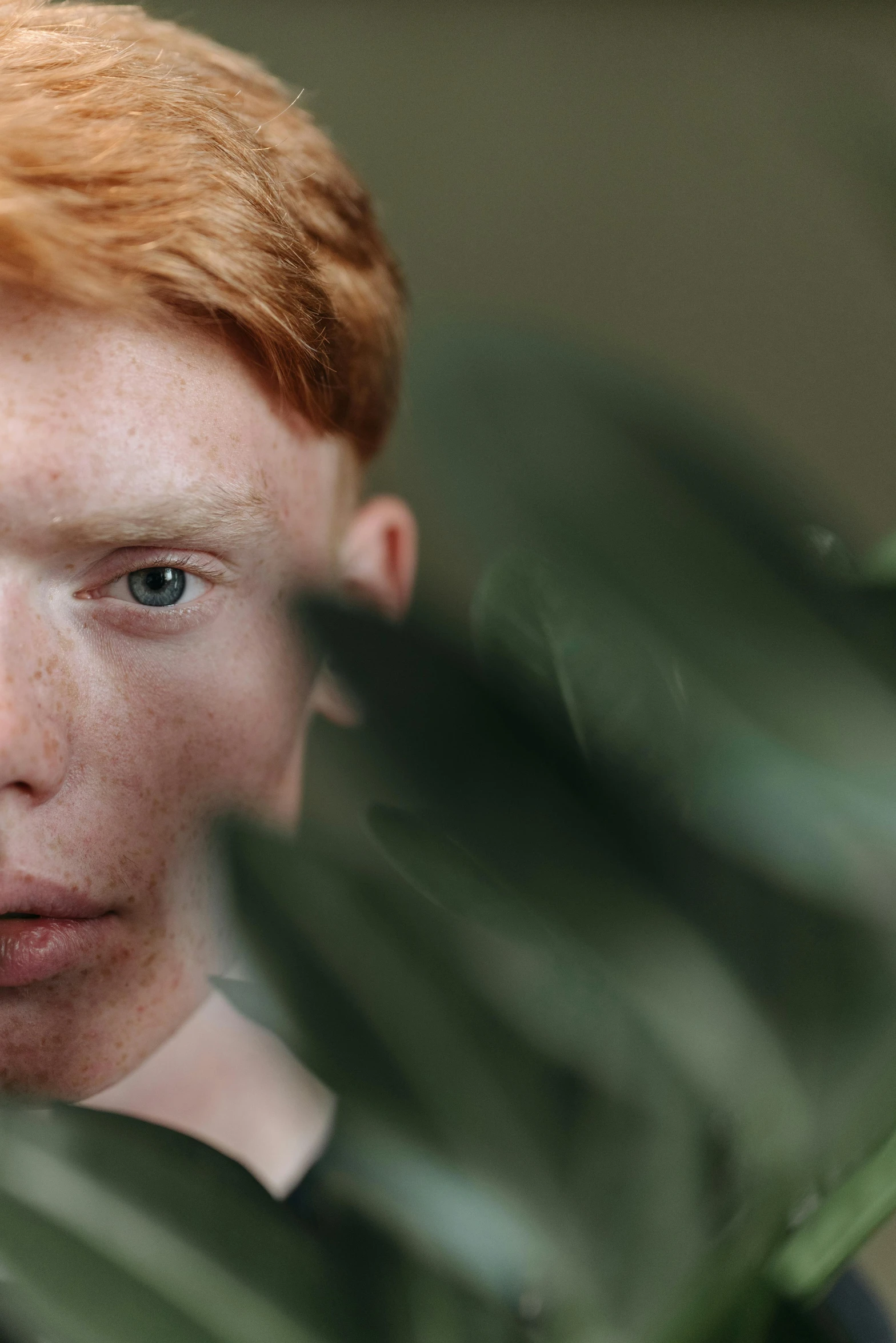 young red - haired boy looking in the mirror while holding a glass