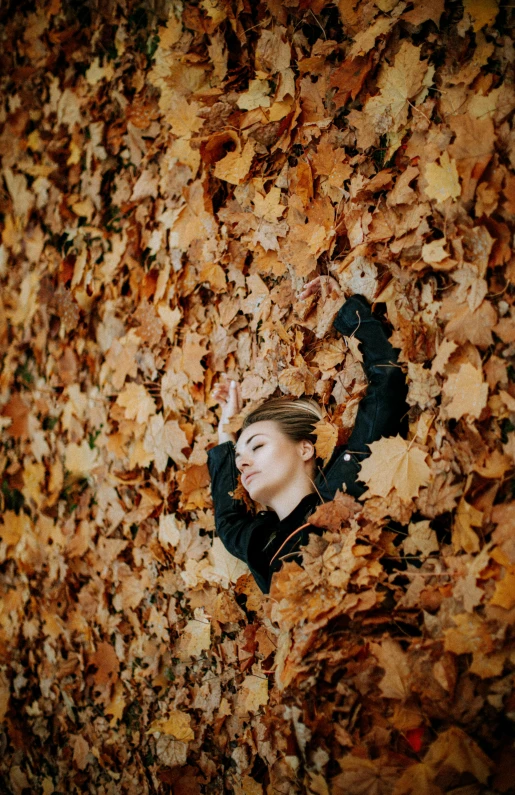 a woman stands in a pile of autumn leaves