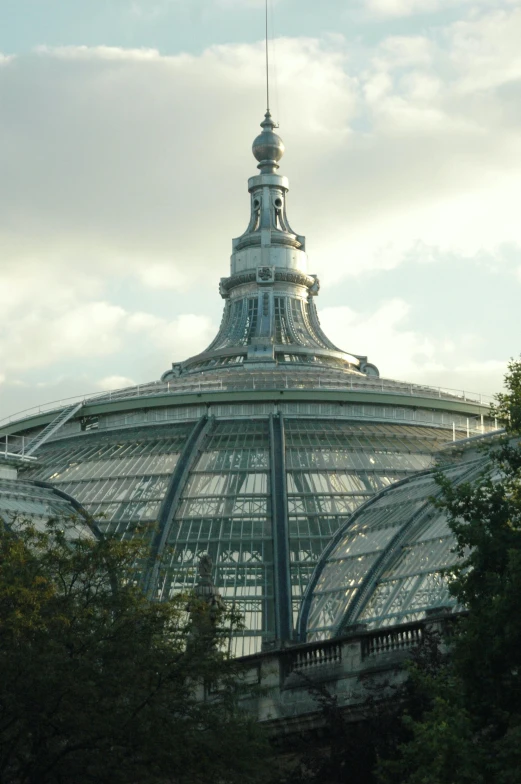 a glass structure with trees surrounding it