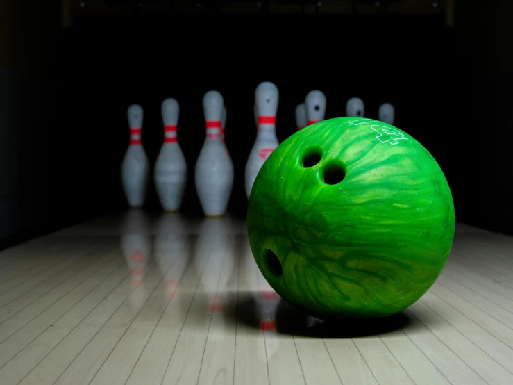 a bowling alley with a green bowling ball going down the side