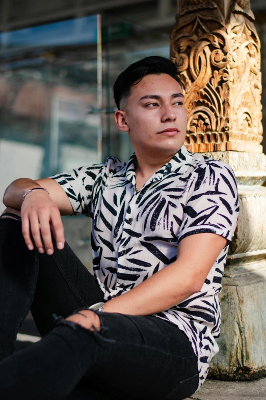 a young man sitting in the middle of a sidewalk