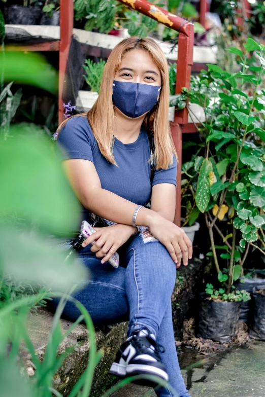 a woman wearing a face mask sitting in a plant shop