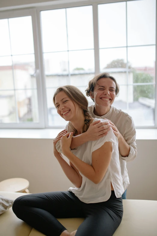 a smiling woman sitting on top of a table next to another girl