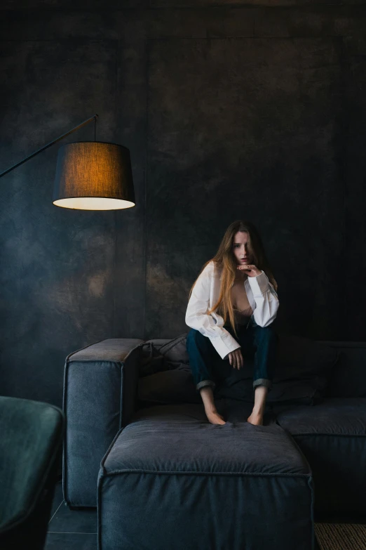 a woman sitting on the foot of a black couch