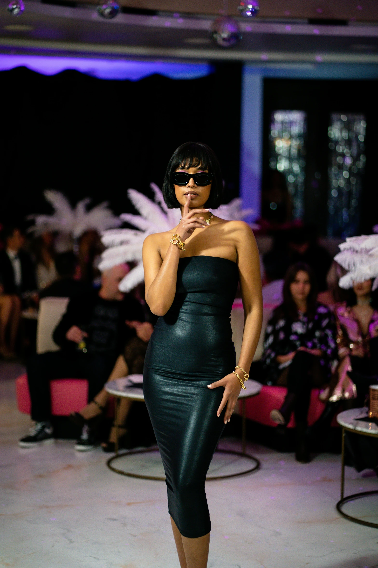 a woman in a black dress standing on a runway