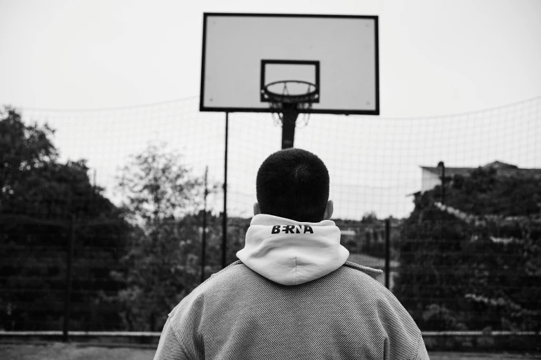 a person is standing by the basket and staring at the basketball hoop