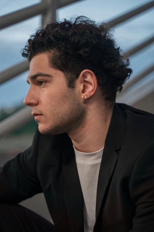 a man wearing a black suit and white t - shirt with a single ear