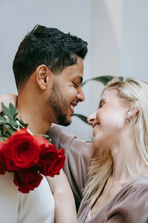 a man is kissing a beautiful woman while they are all holding red flowers