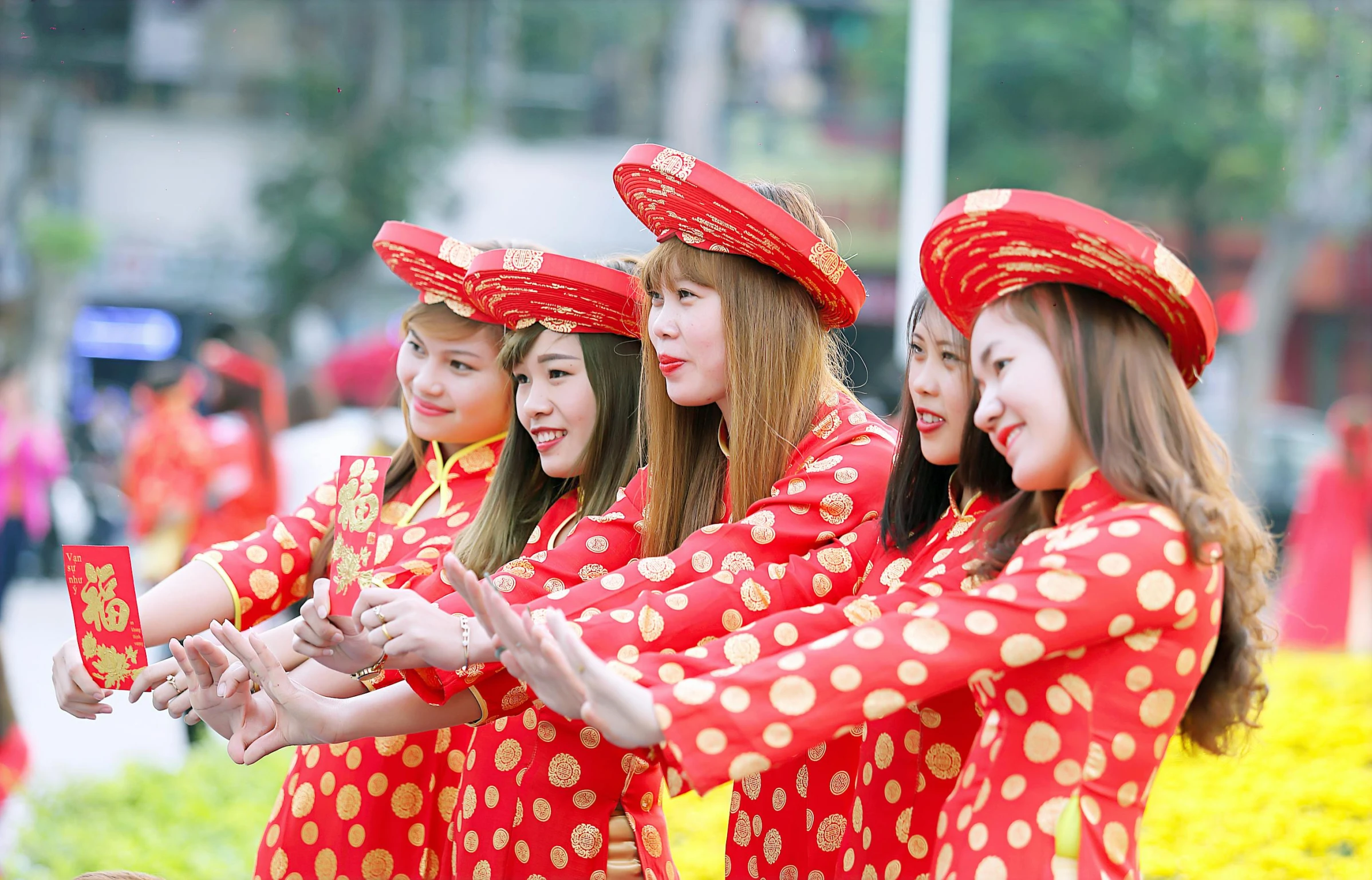 girls in red vietnamese garb are singing at the street