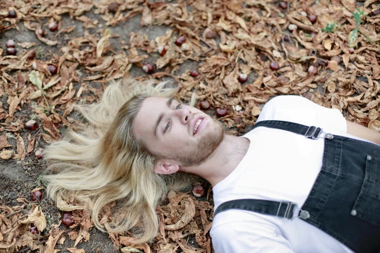 a young man sitting on top of leaf covered ground