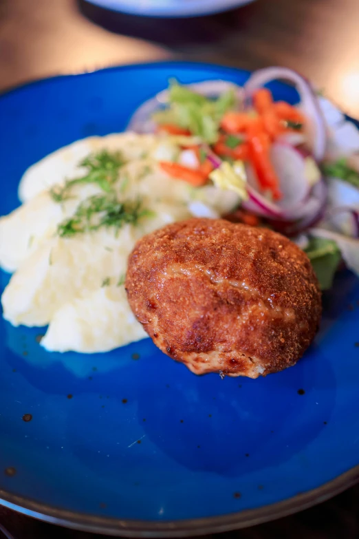 a blue plate with potatoes and meatballs