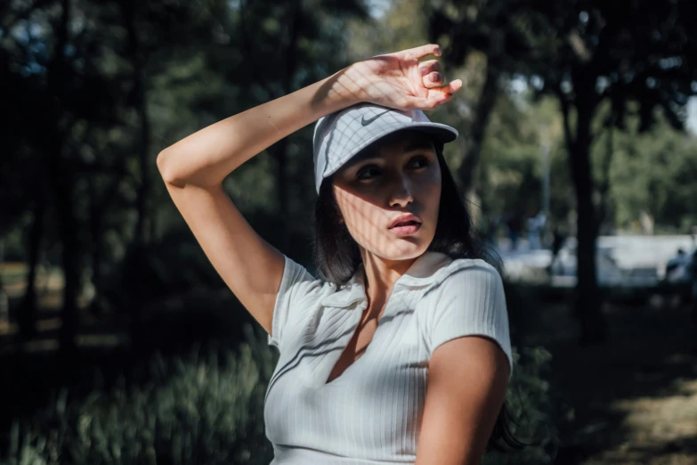 a young woman wearing a hat while holding her hands up to her head