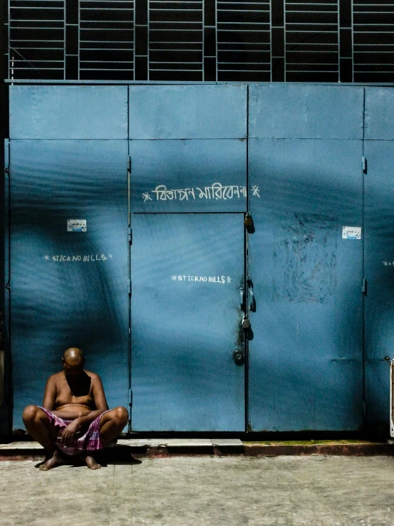 a person sitting on the ground in front of a building