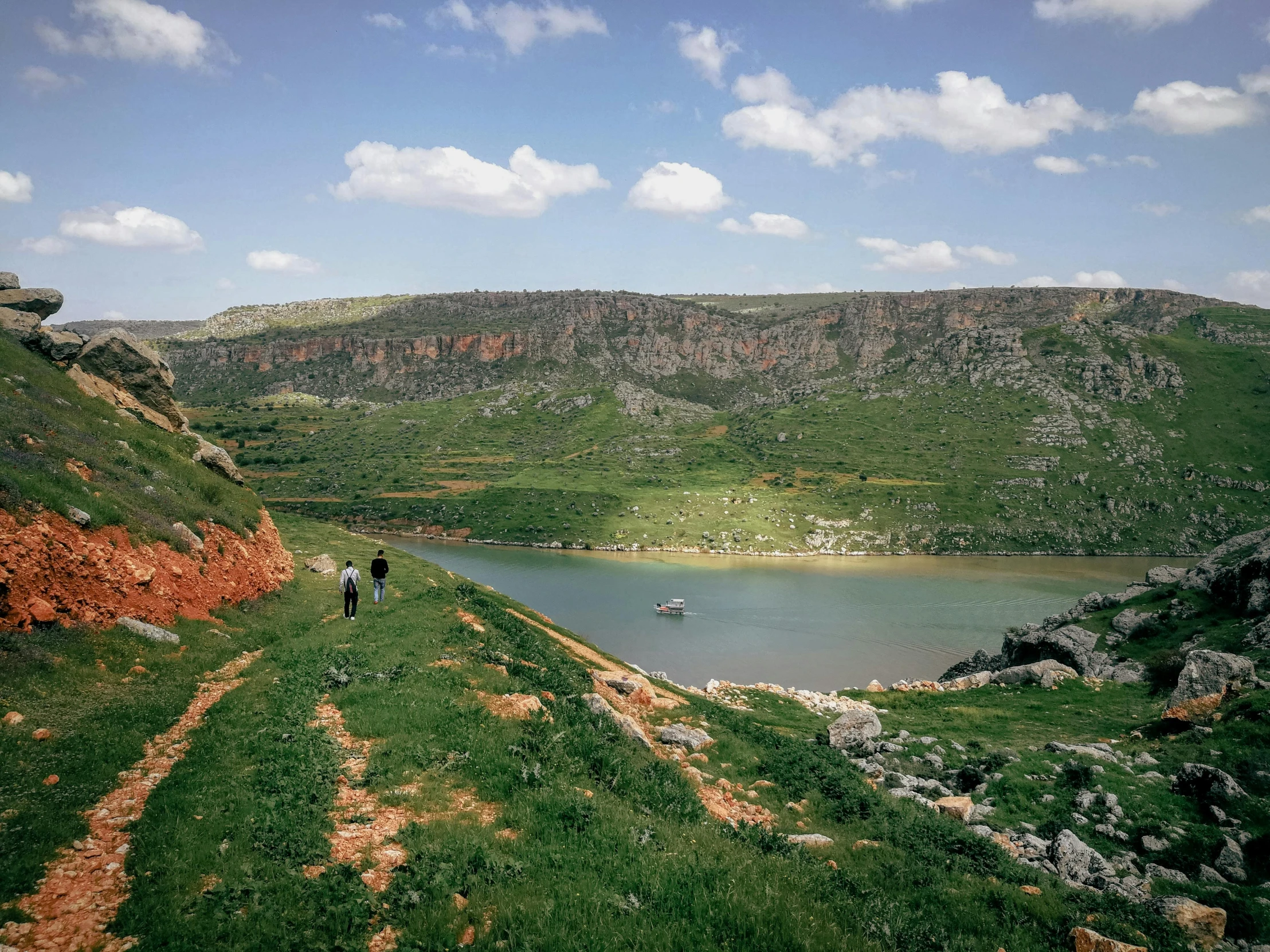 two people stand on a hill overlooking a lake and mountain