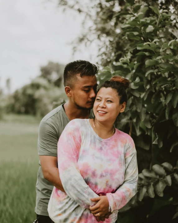 couple hugging each other in the middle of a grassy field