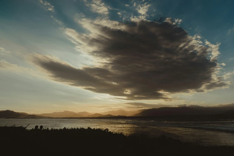 the view of a beach during sunrise with very cloudy skies