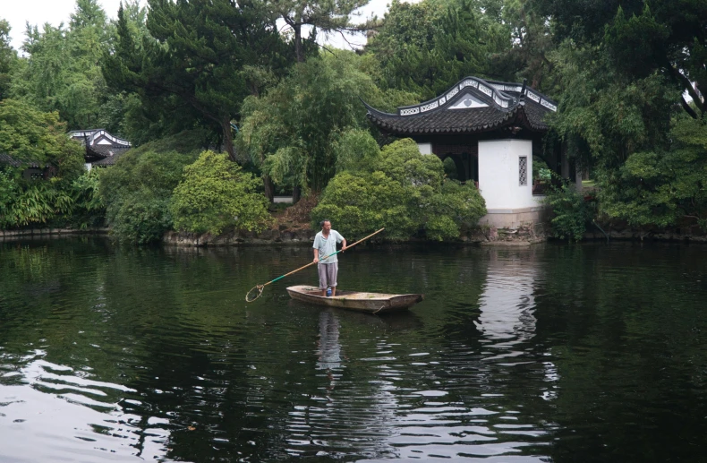 an asian man paddles his boat across the water