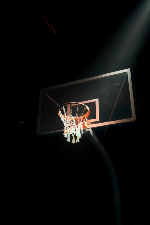 a basketball hoop is lit up by a spot light