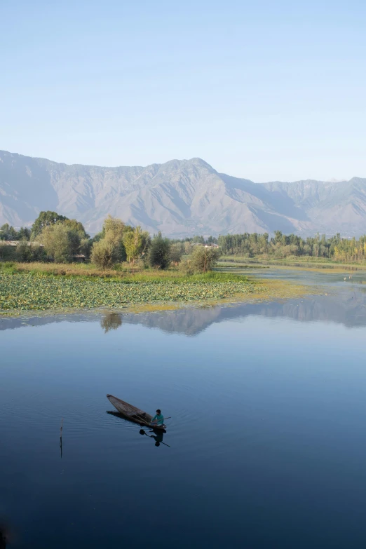 a lone boat sits on the water in front of mountains