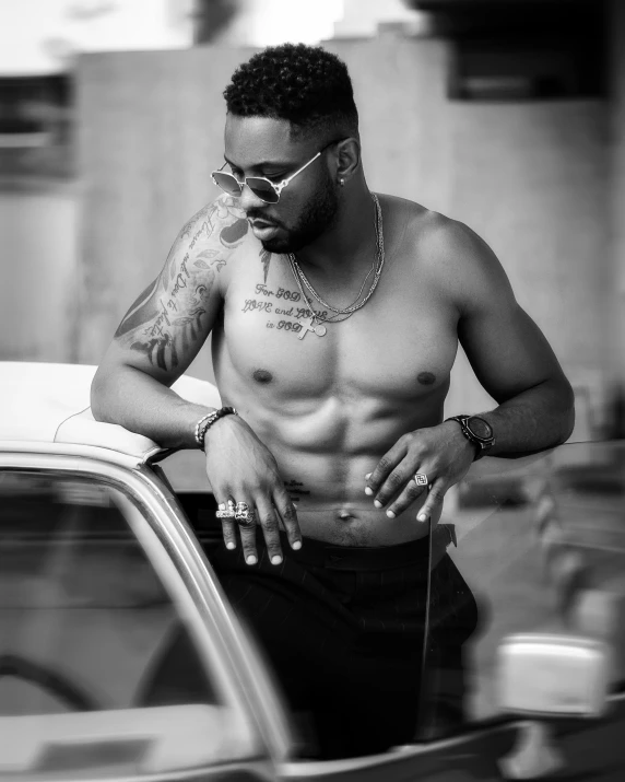 a man with tattoos smoking while standing next to a car