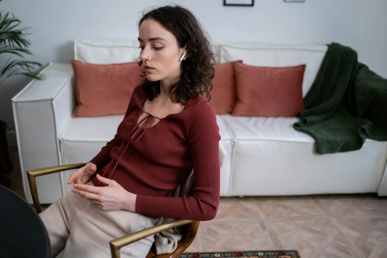 a woman is sitting on a chair and holding her hands together