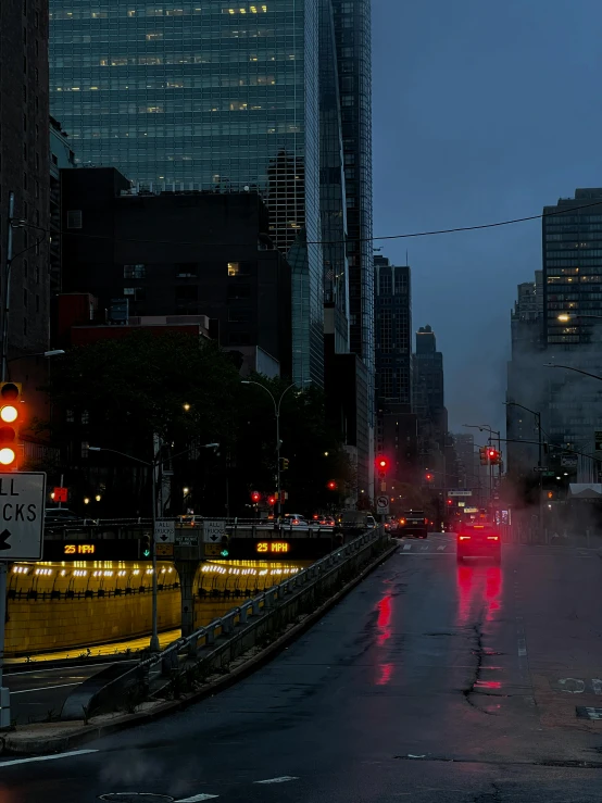 a street in the rain with red lights and cars